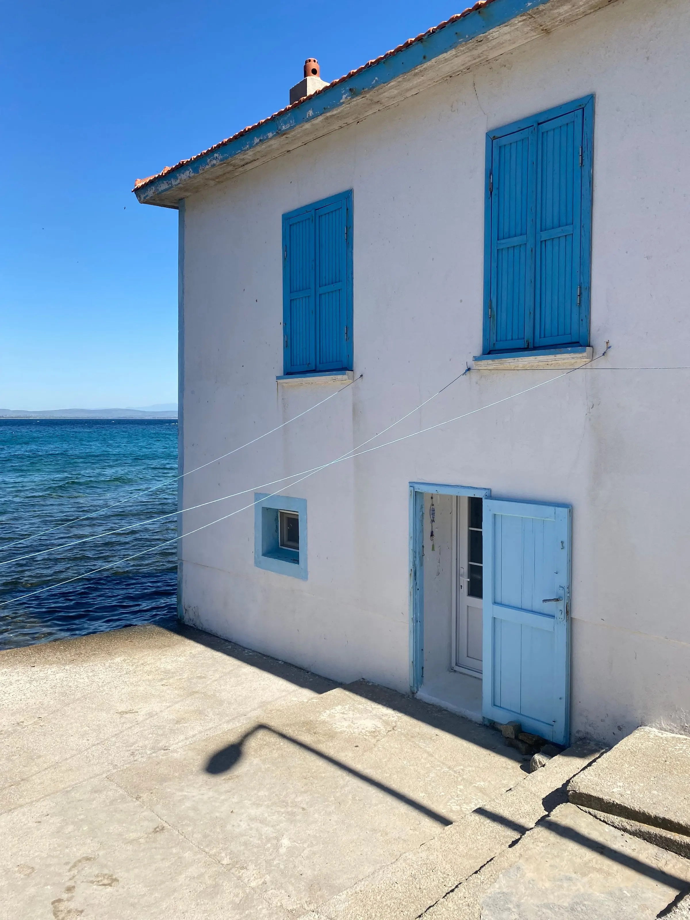 La casa: due piani di calce bianca con le persiane azzurre, il mare a pochi passi e i panni stesi al sole