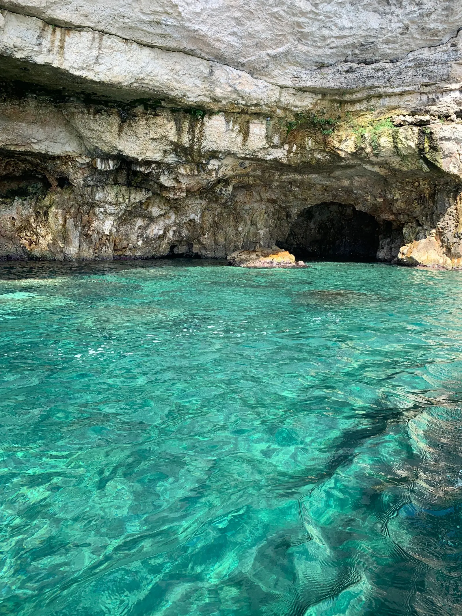 Acqua turchese e trasparente davanti all'ingresso di una grotta nella roccia