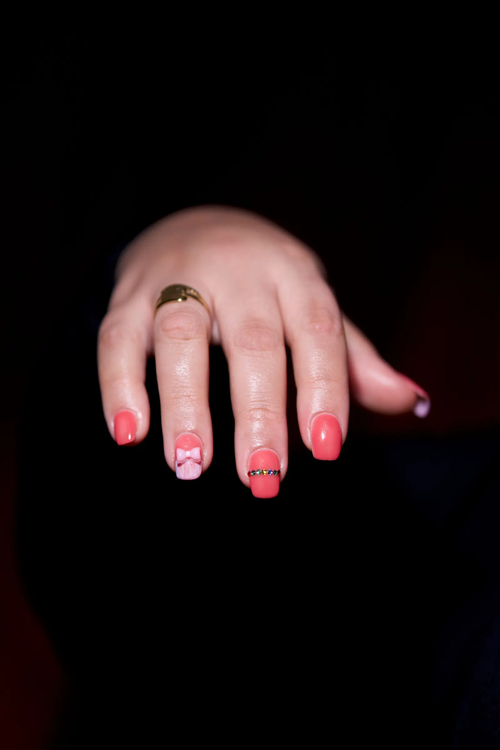 Unghie rosa con piccoli fiori disegnati a mano, su fondo nero