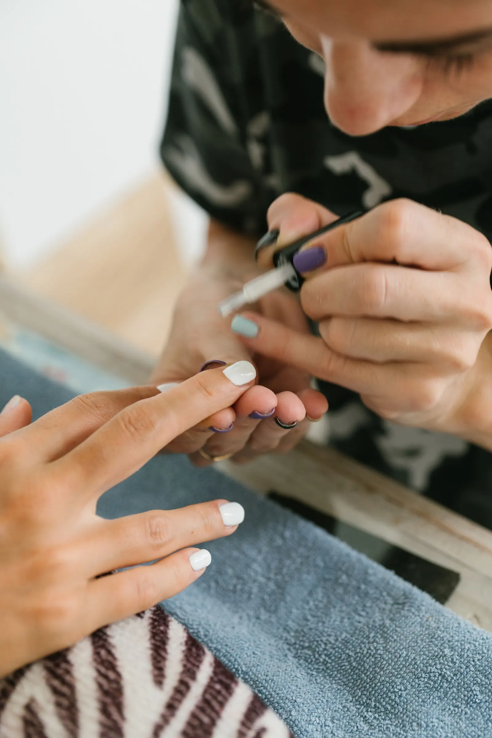 Una manicurista stende lo smalto bianco sull'unghia di una cliente