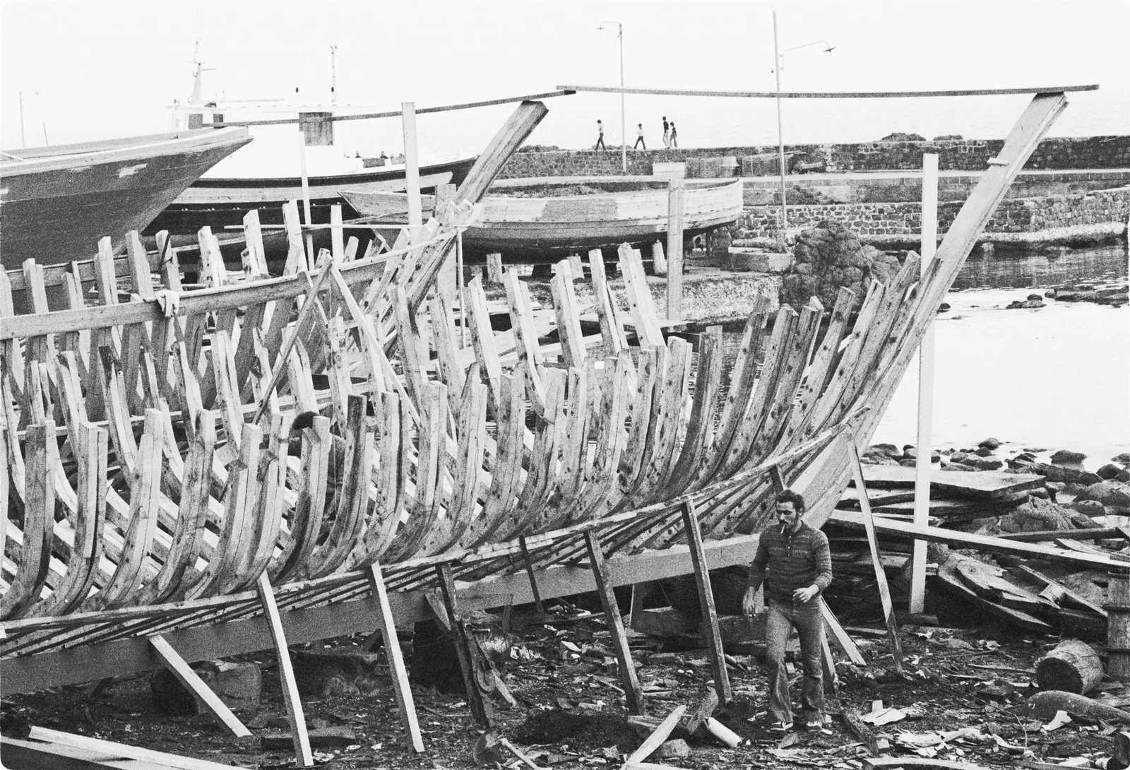 Ossatura di una barca in legno in costruzione su una spiaggia: chiglia, ordinate e puntelli, in bianco e nero