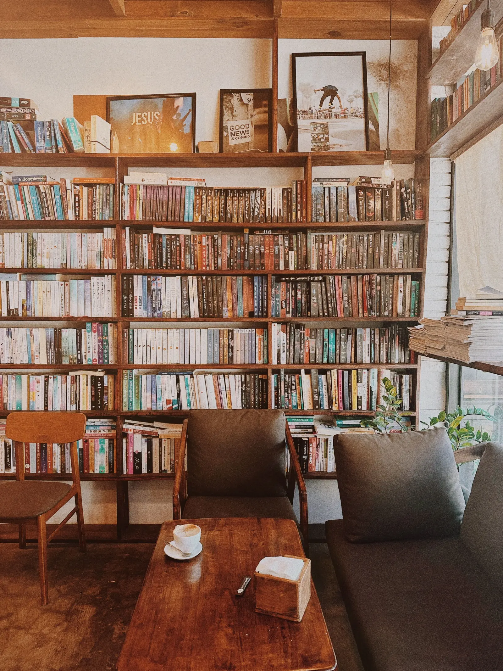 La sala della libreria: scaffali di legno pieni di libri, una poltrona, un divano e un cappuccino sul tavolino