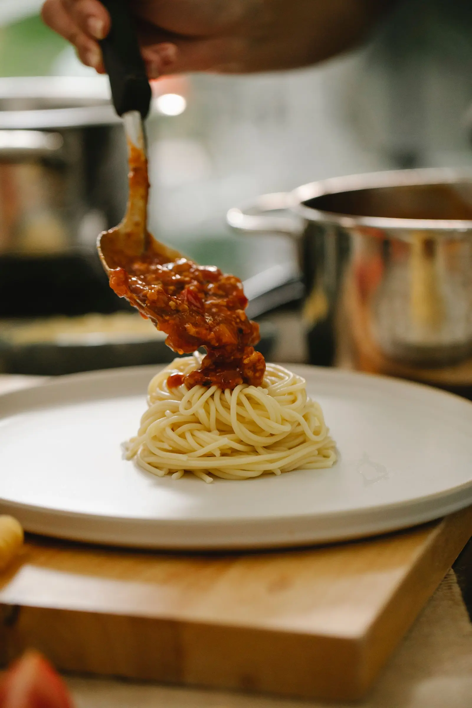 Il sugo versato col mestolo su un nido di spaghetti nel piatto bianco