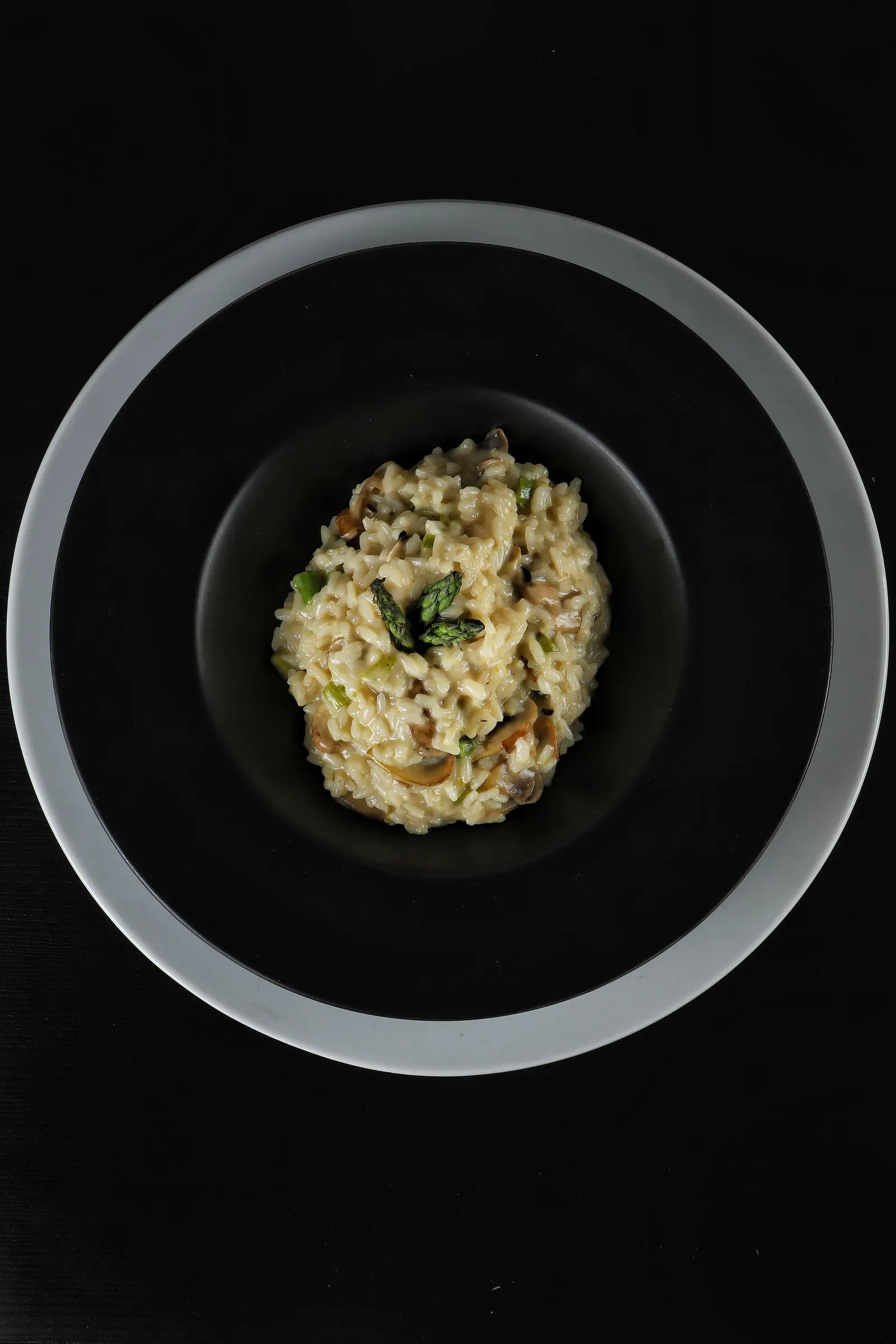 Risotto con funghi in una ciotola nera, visto dall'alto