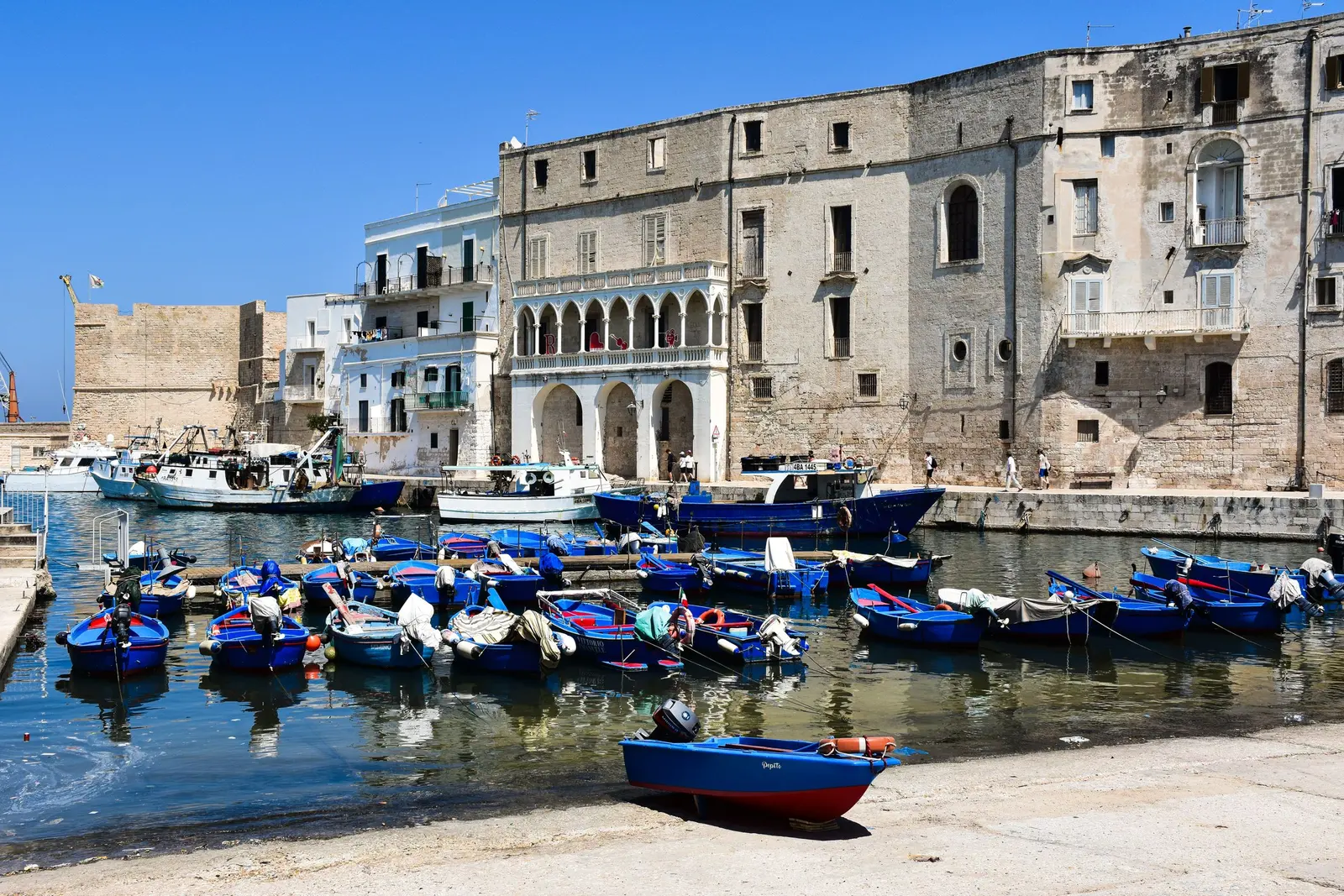 Il porto antico di Monopoli con le barche blu dei pescatori davanti ai palazzi in pietra