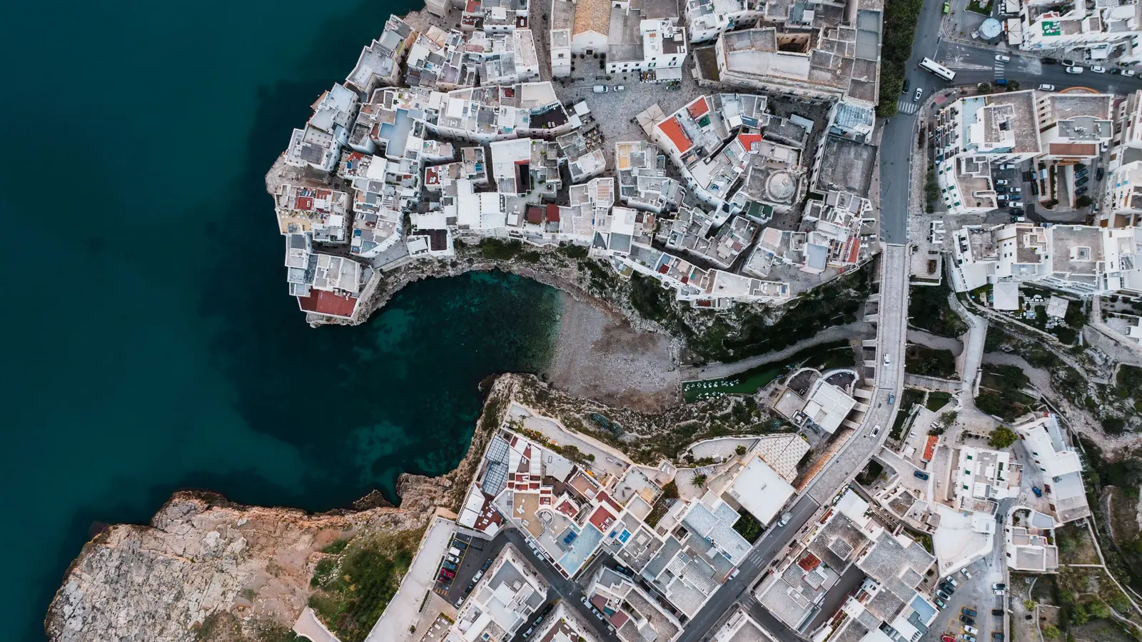 Polignano a Mare vista dall’alto: la cala tra le rocce, il ponte e le case bianche sul bordo della falesia