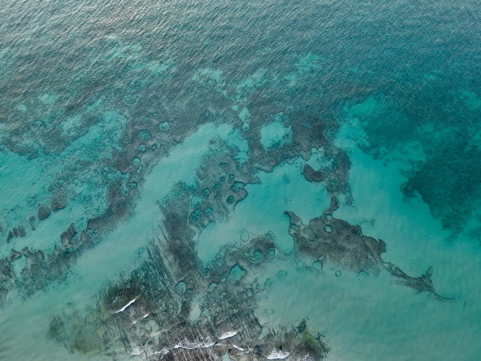 Acqua turchese su un fondale basso di roccia, vista dall’alto