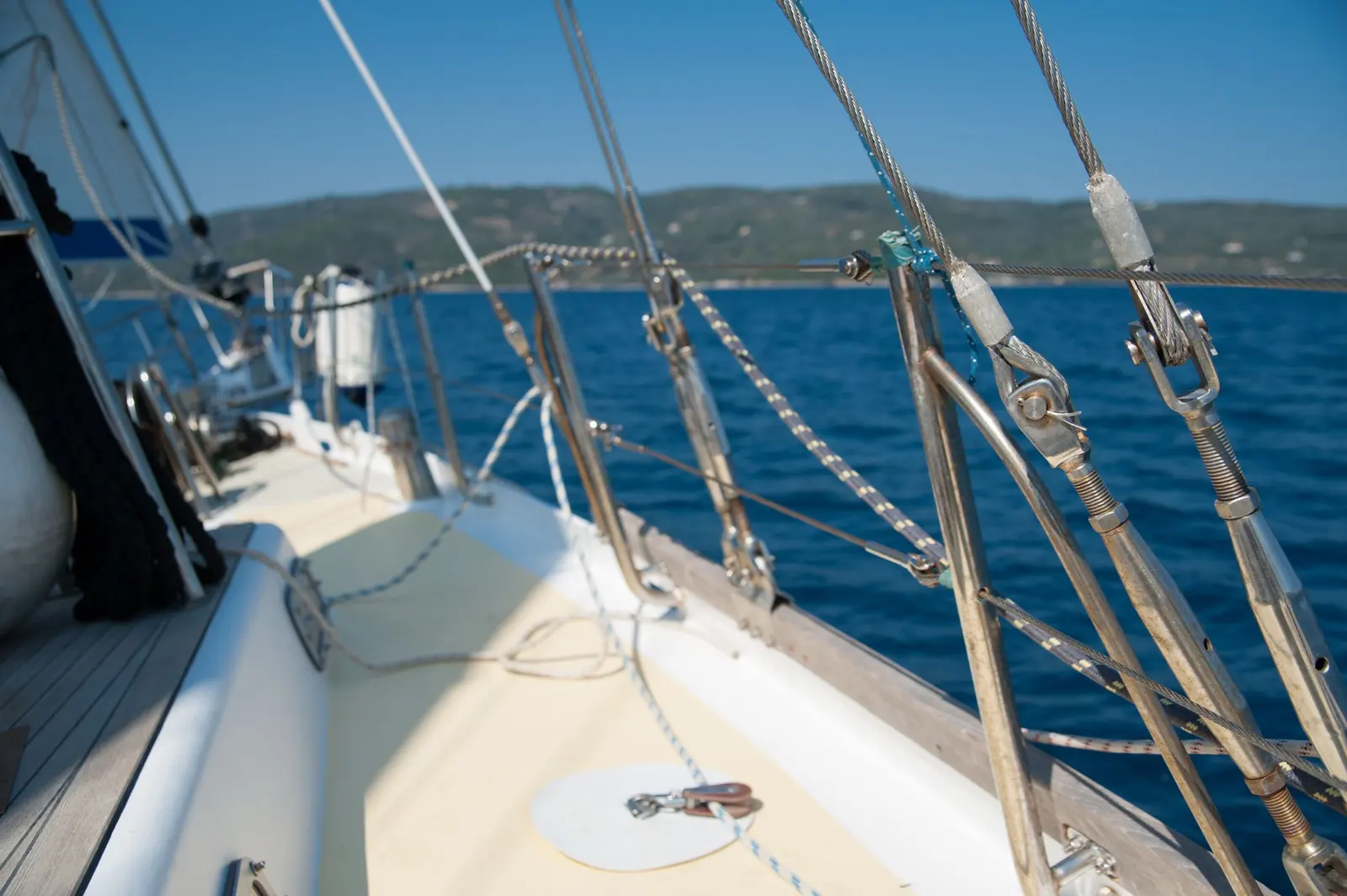 Coperta di una barca a vela in navigazione: draglie, sartiame e mare blu