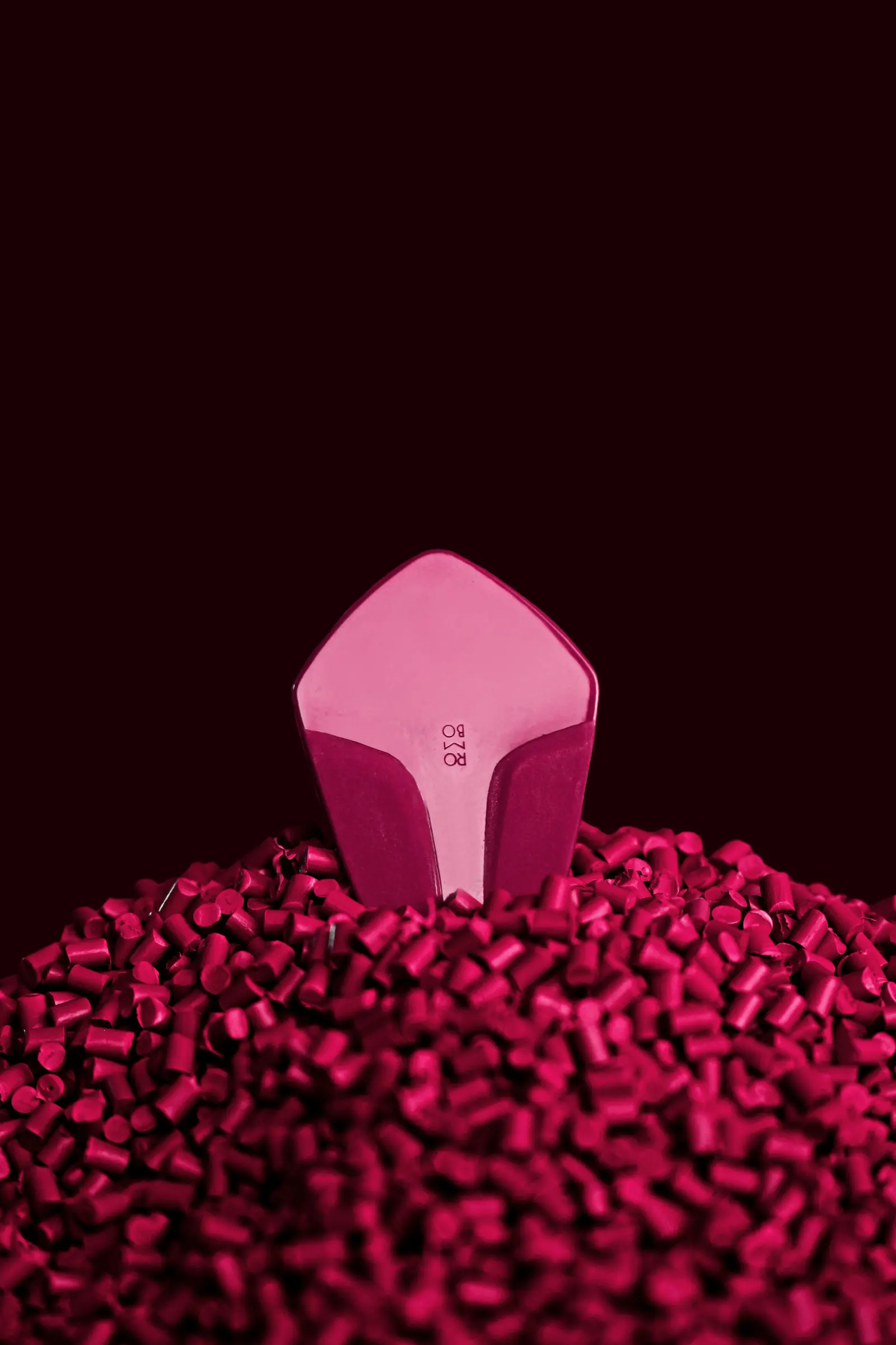 Un pezzo stampato in due toni di rosa appoggiato su un mucchio di granuli magenta, fondo scuro