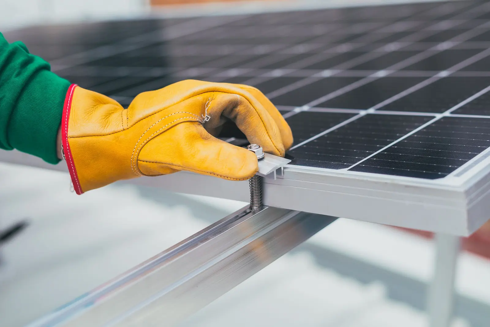 Mano con il guanto da lavoro che stringe il morsetto sul telaio di un modulo