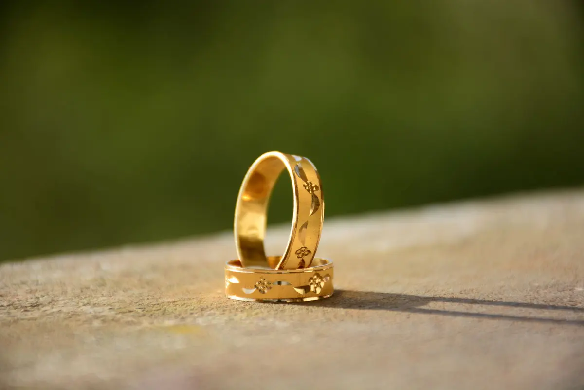 Due anelli d'oro intrecciati appoggiati su una pietra