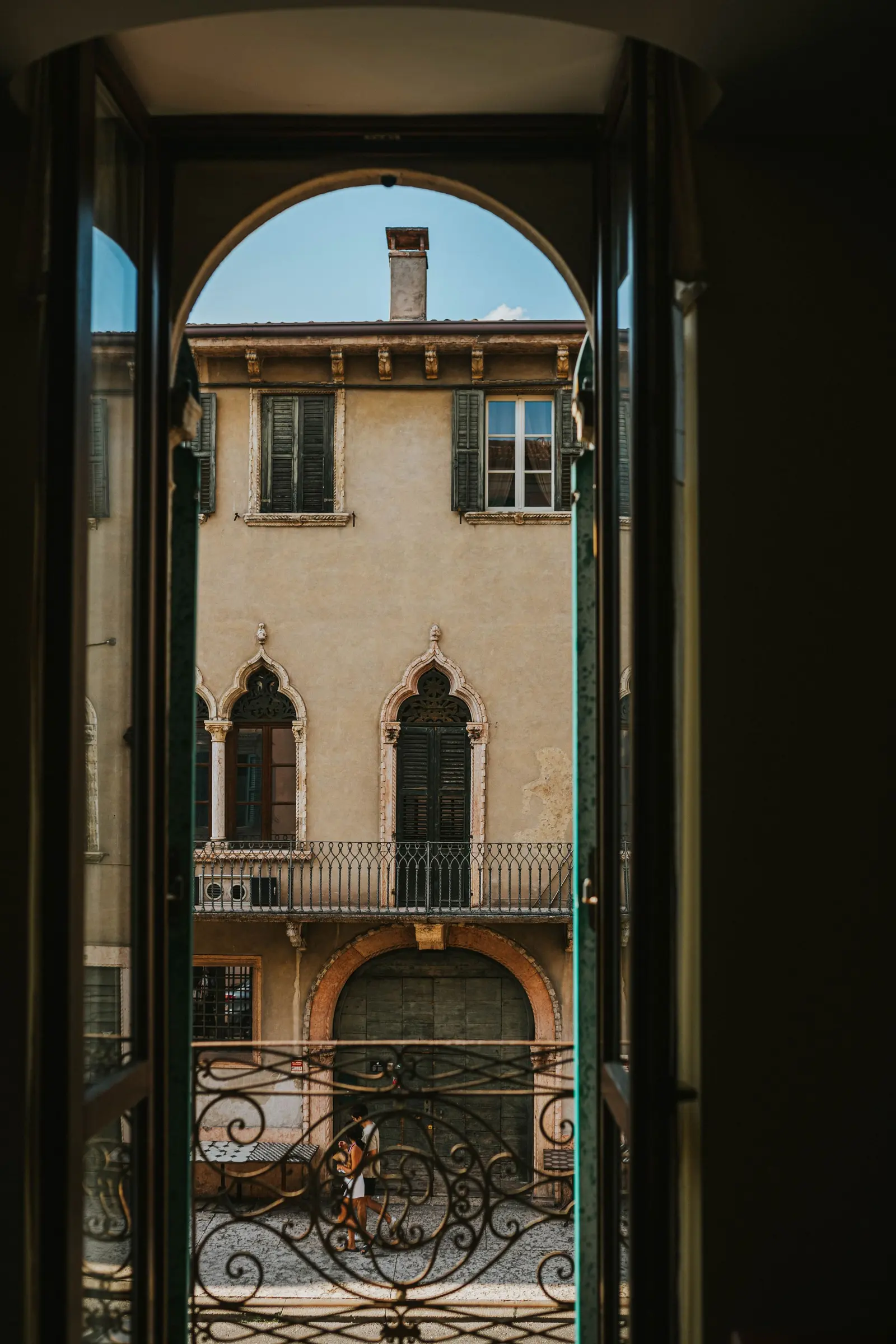 Finestra aperta su una facciata di pietra chiara con un balcone in ferro battuto
