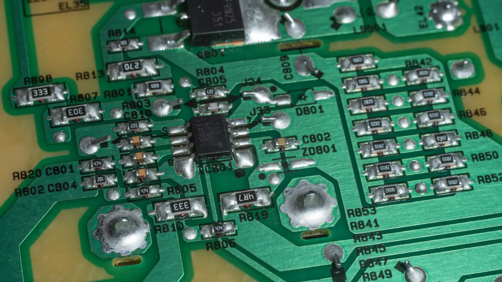 Primo piano di una scheda elettronica verde con i componenti saldati