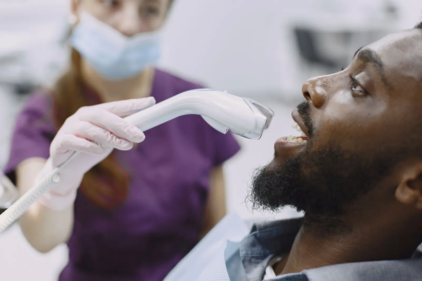 La dentista avvicina la lampada fotopolimerizzatrice alla bocca del paziente
