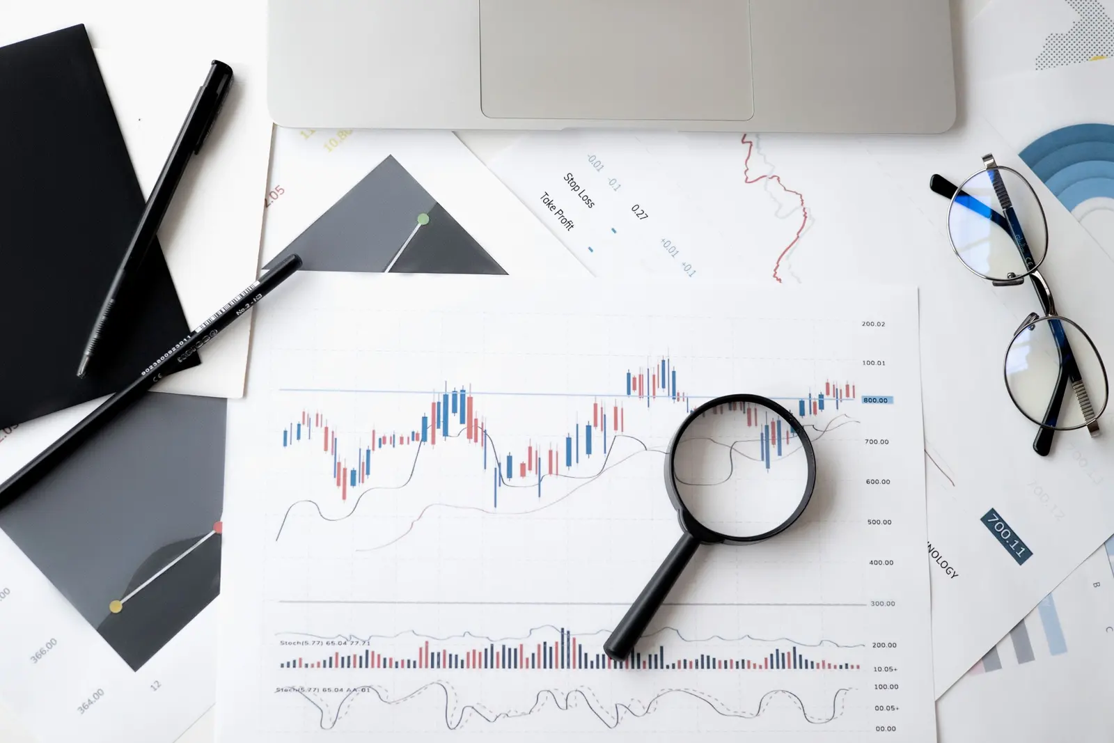 Lente d'ingrandimento appoggiata su fogli di grafici e tabelle