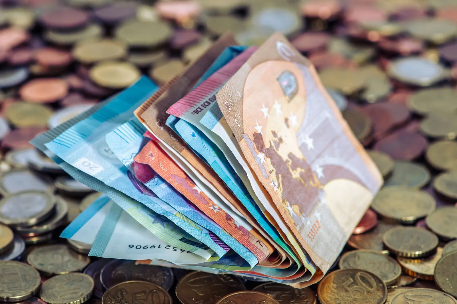Banconote in euro a ventaglio su un tappeto di monete