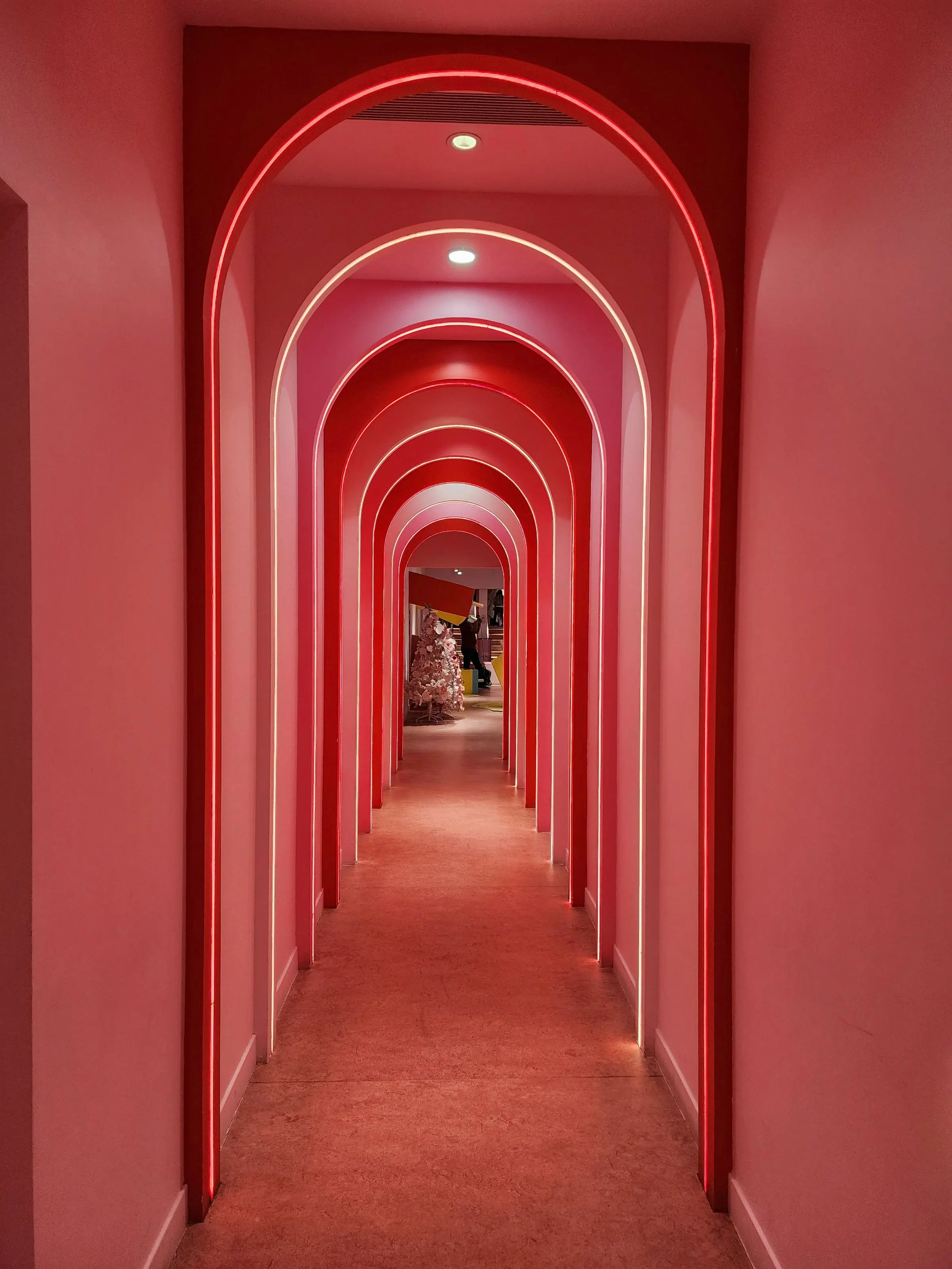 Corridoio di archi rosa illuminati in successione verso il fondo