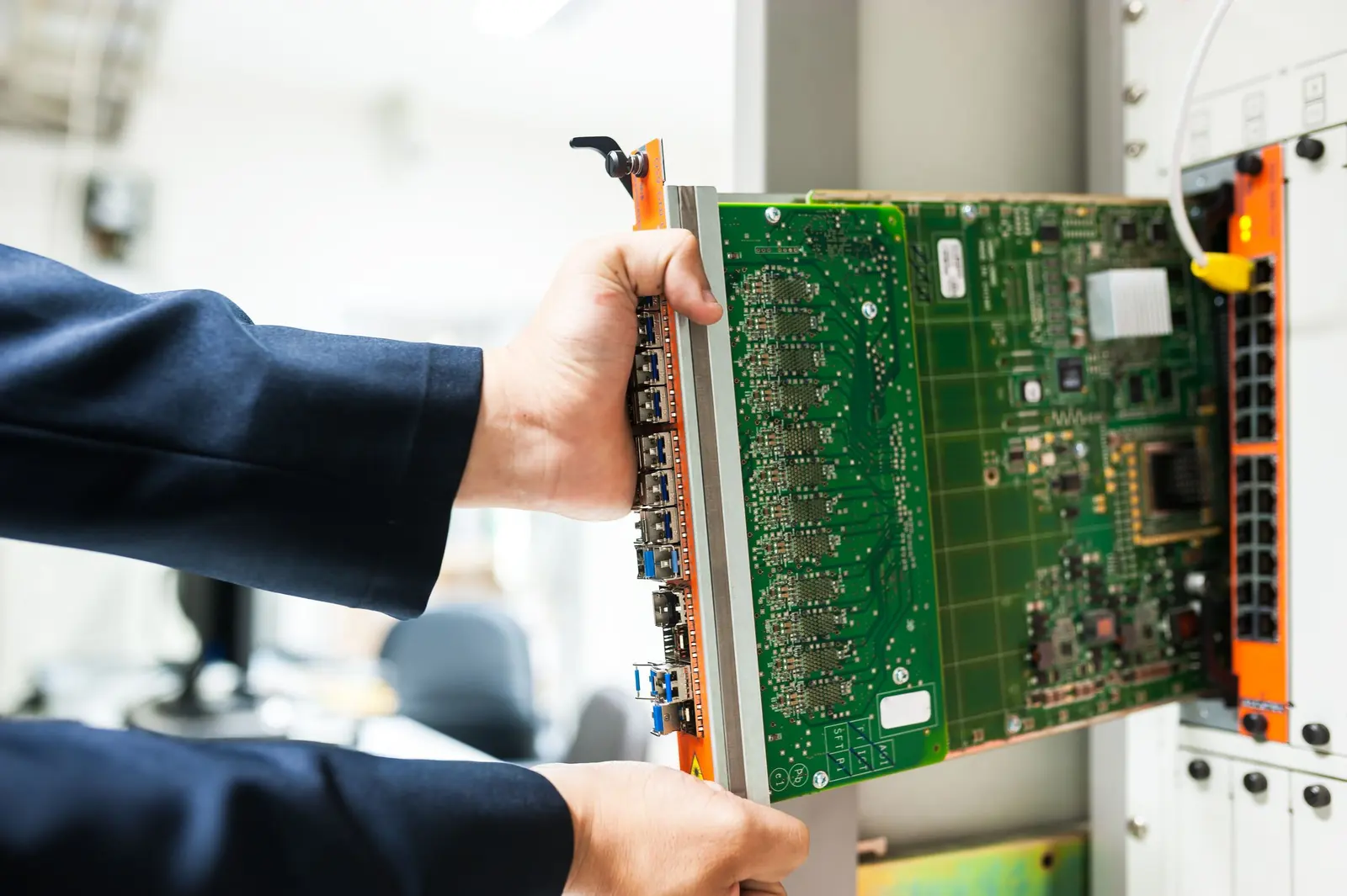 Una mano inserisce una scheda elettronica in un rack di apparati