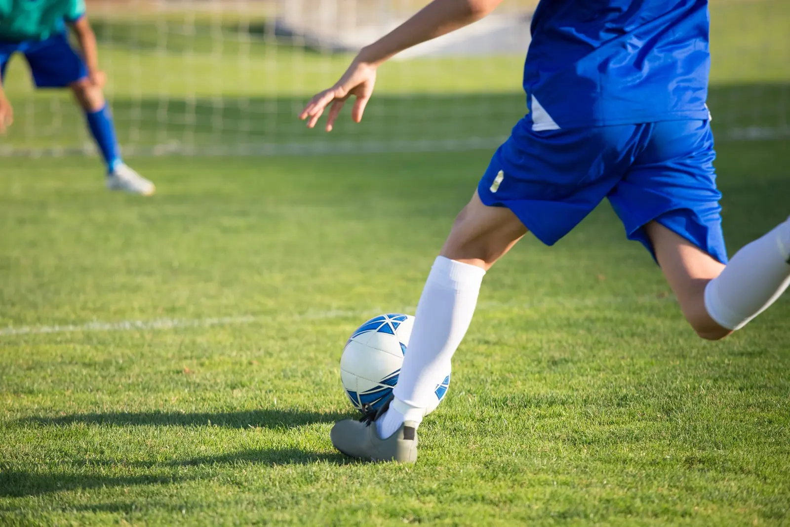 La gamba di un ragazzo che calcia il pallone, da vicino