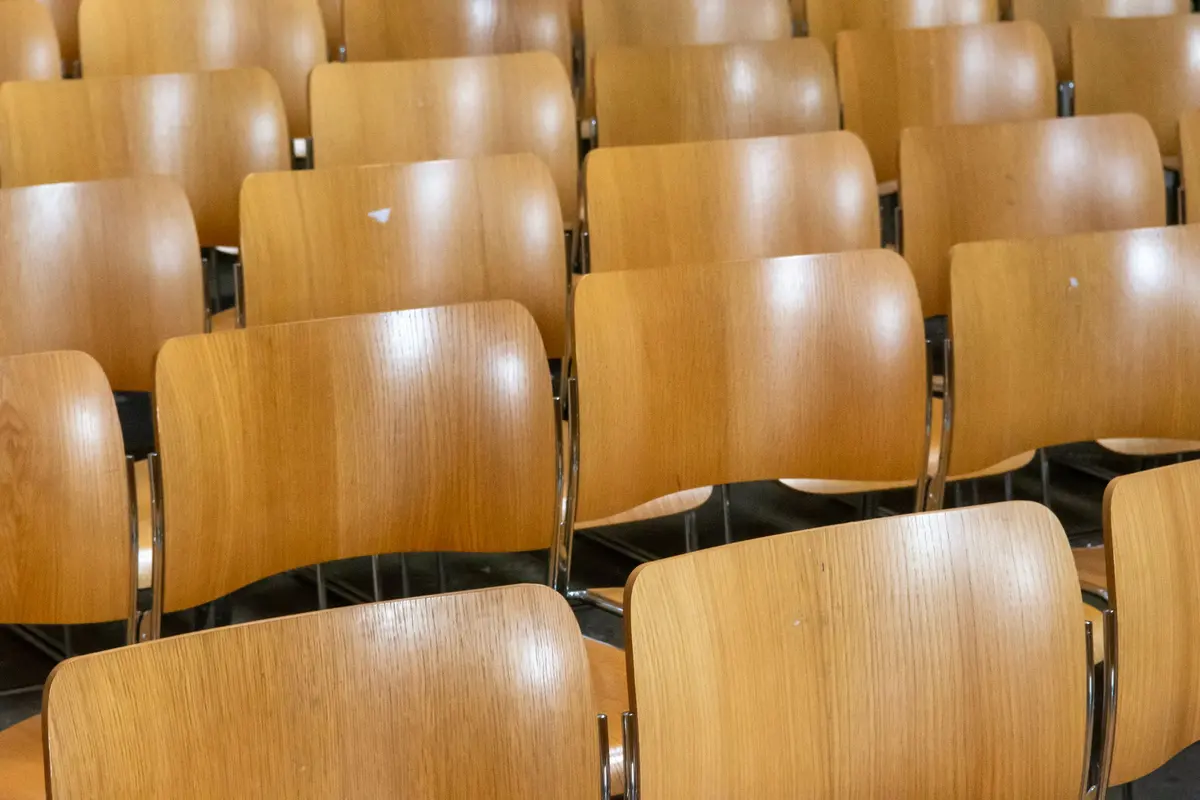 File di sedie in legno vuote in una sala riunioni