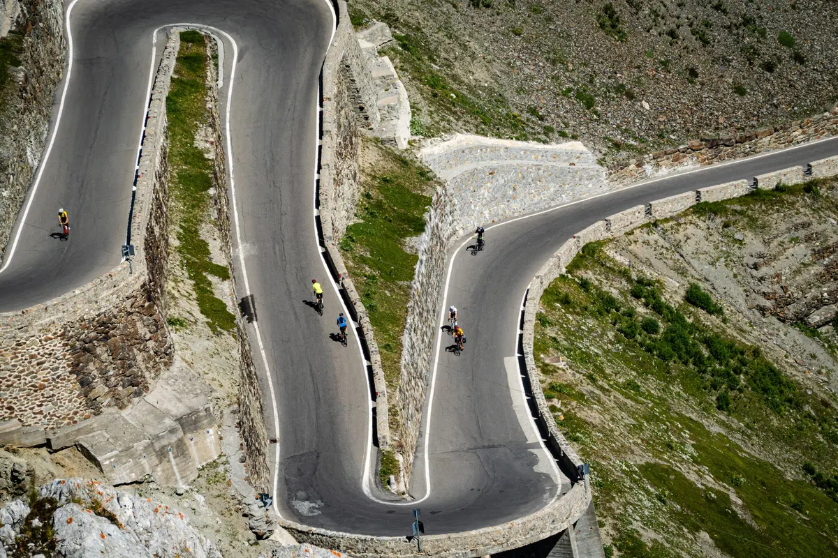 Ciclisti sui tornanti di una strada di montagna visti dall'alto
