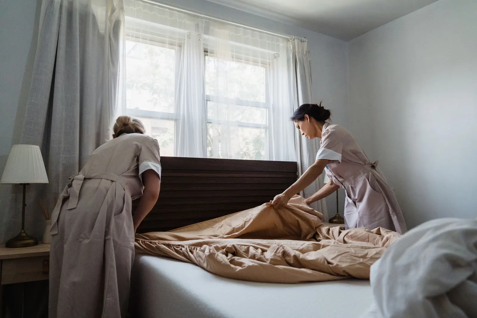Due cameriere ai piani rifanno il letto di una camera d'albergo luminosa