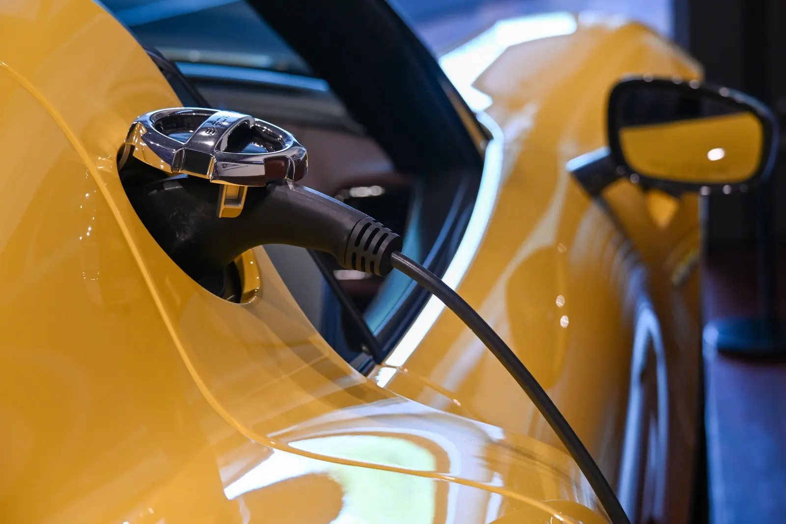 Connettore di ricarica inserito nella fiancata di un'auto gialla
