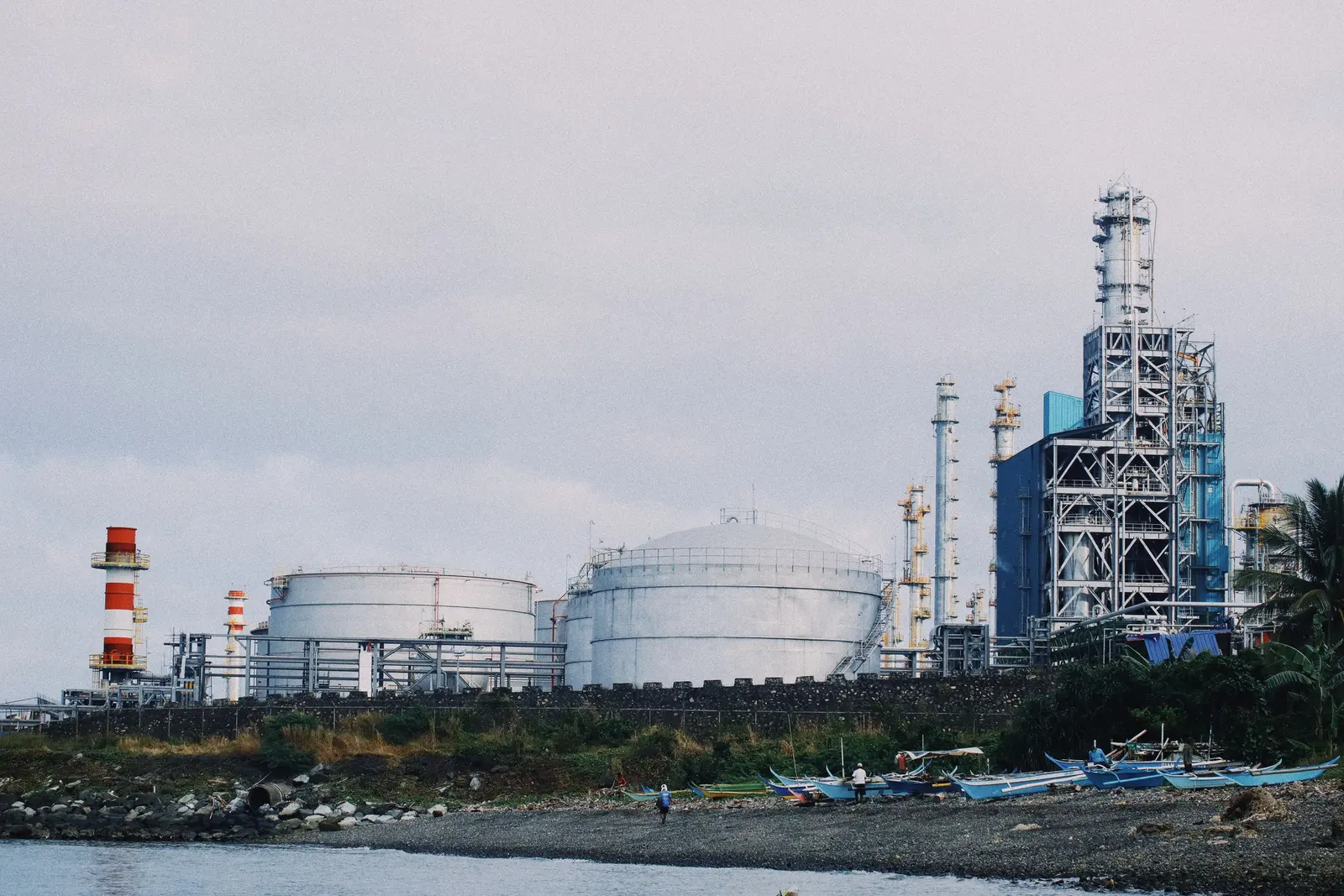 Un impianto petrolchimico sulla costa, con serbatoi bianchi e colonne di distillazione