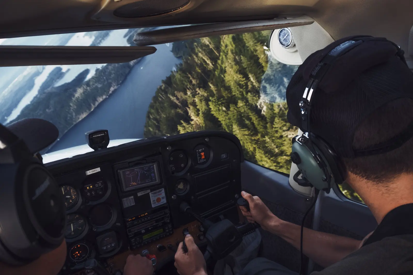 Dalla cabina: istruttore e allievo in volo sopra un fiume tra i boschi