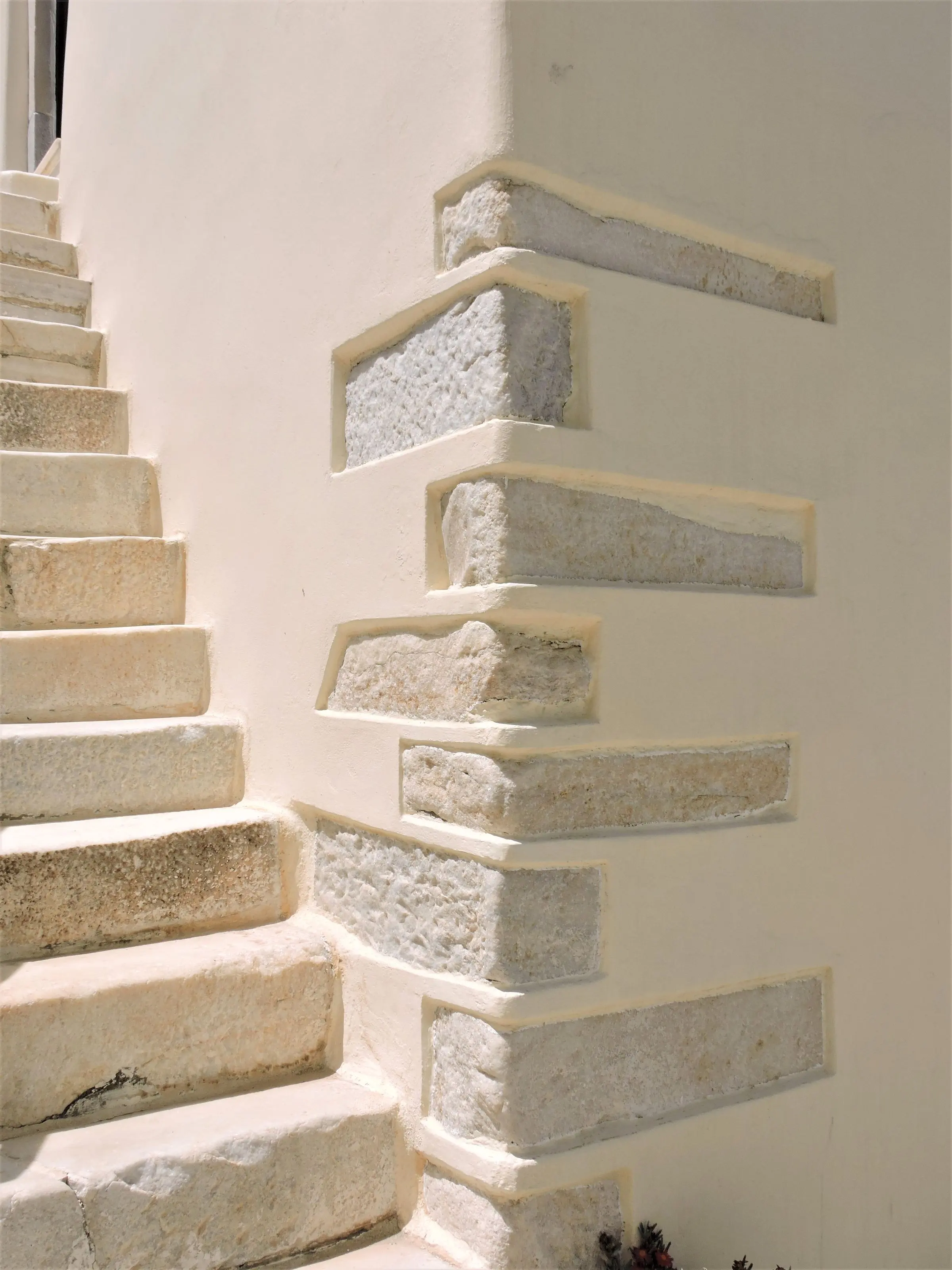 Scala esterna in pietra lungo un muro bianco a calce, con i blocchi d'angolo in pietra a vista
