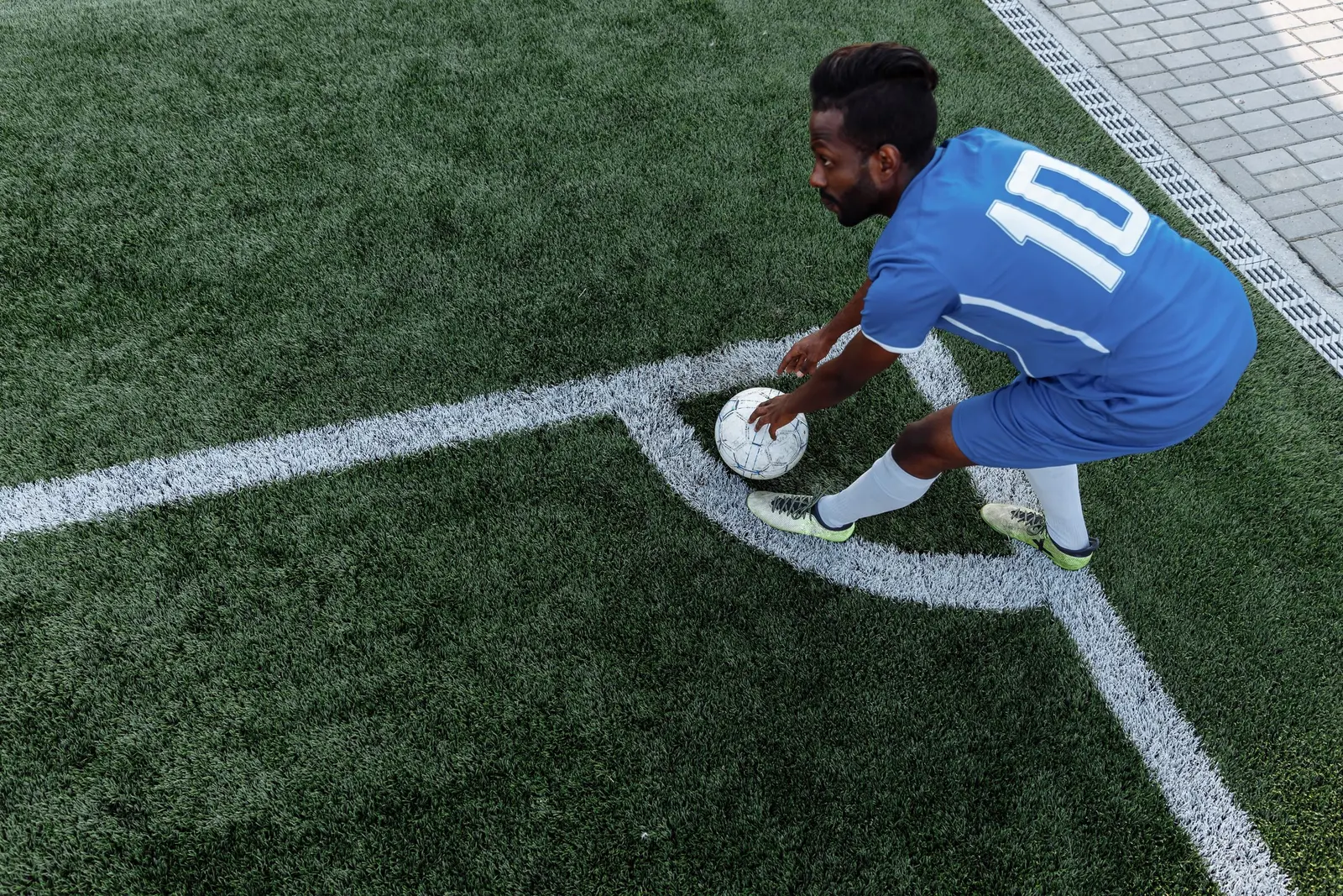 Un giocatore con la maglia blu numero 10 sistema il pallone nell'angolo del campo per il calcio d'angolo