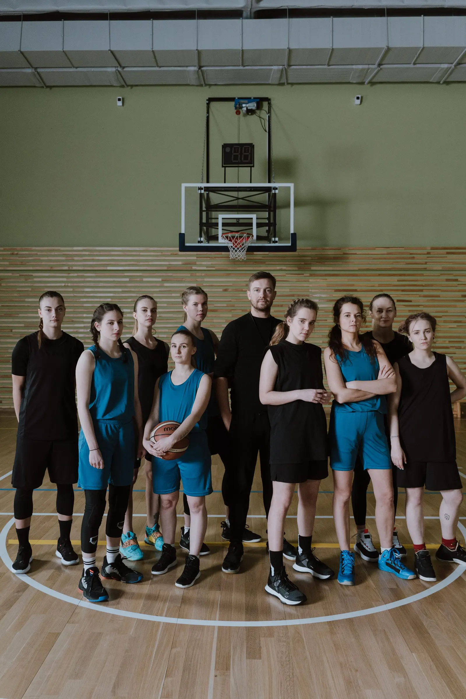 Una squadra di basket in posa sotto il canestro, canotte nere e verde acqua