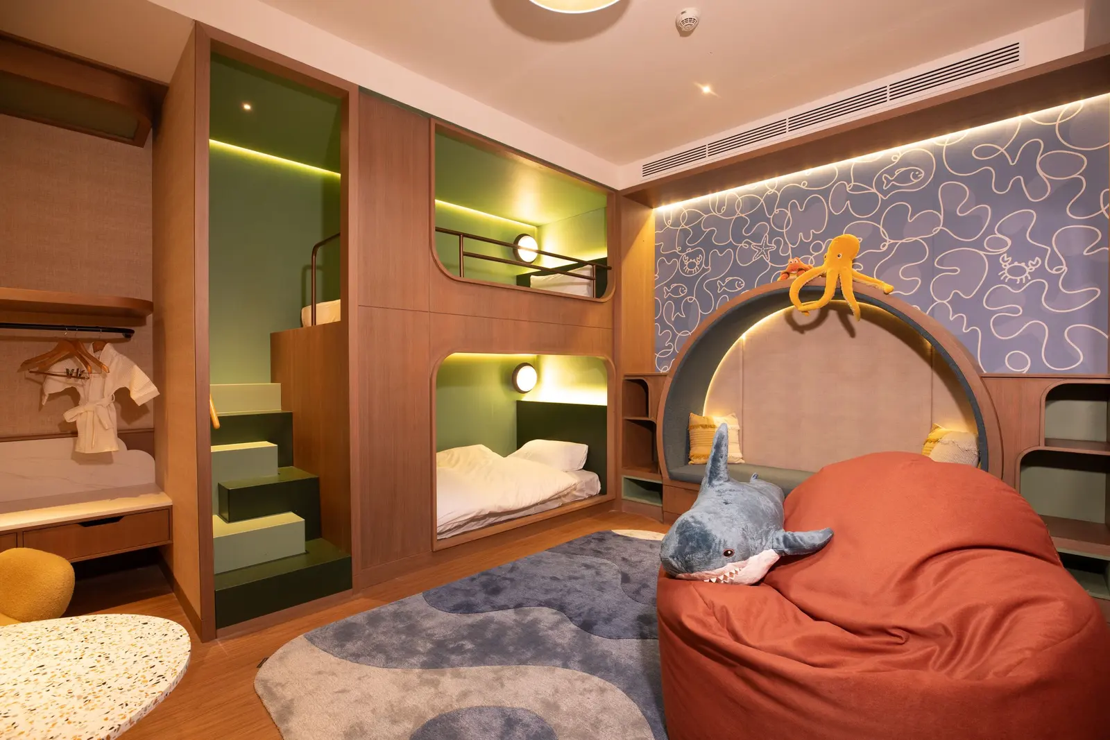 Camera dei bambini con due letti a castello incassati nella parete e un grande pouf arancione