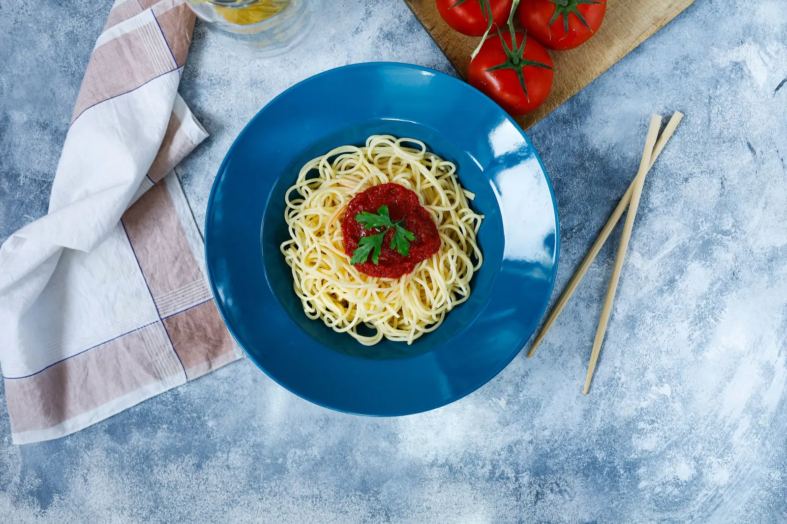 Spaghetti al pomodoro con il basilico in un piatto blu, visti dall'alto