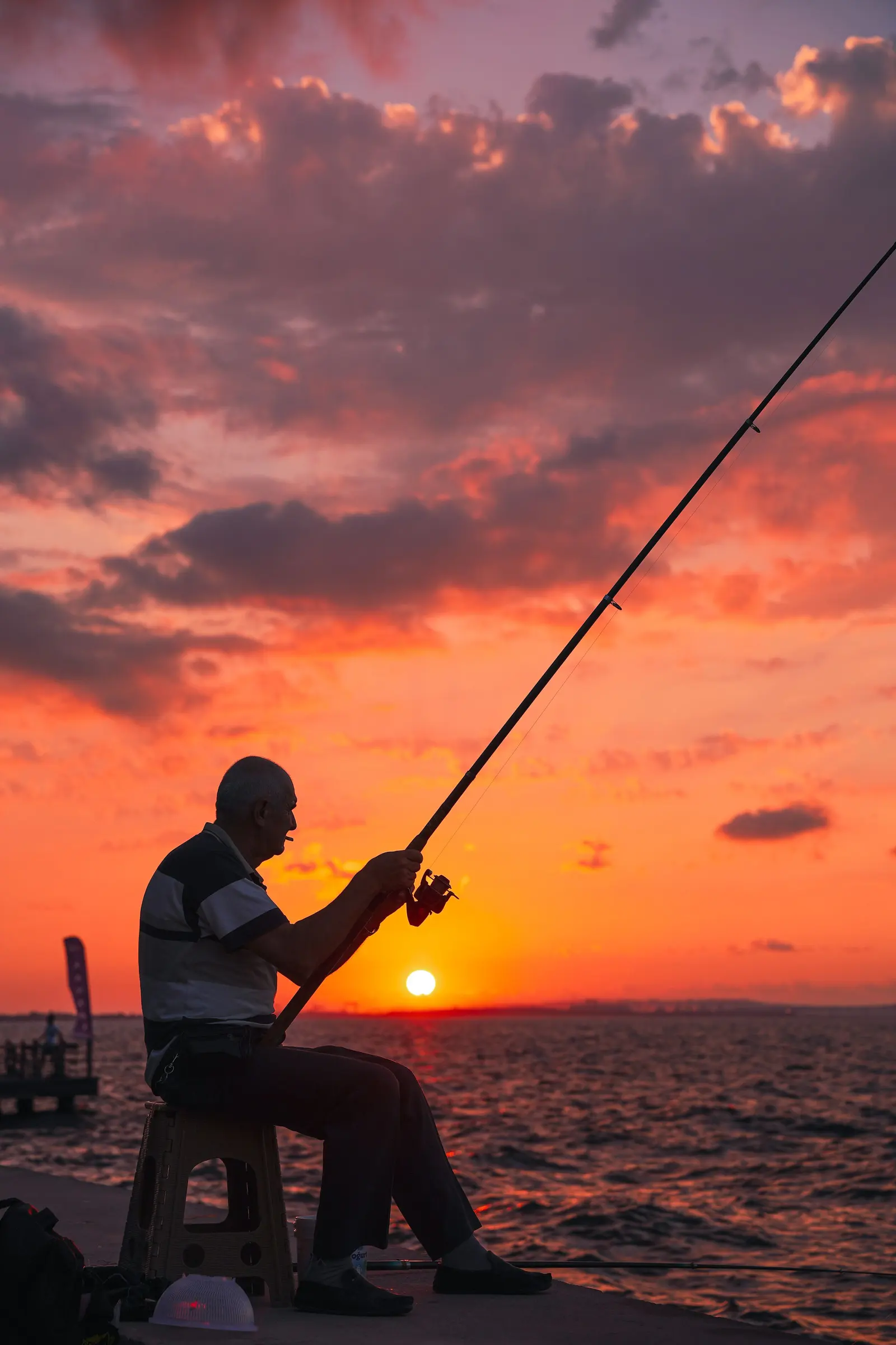 La sagoma di un pescatore con la canna sul mare al tramonto