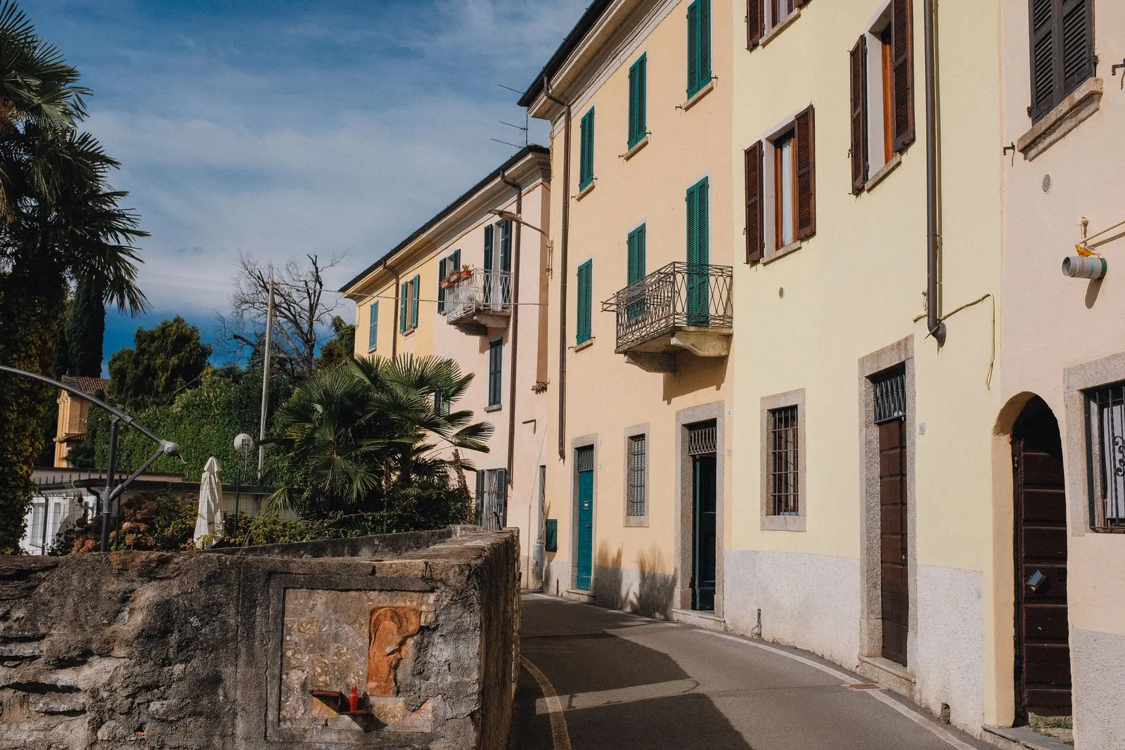 Una via di paese con case color crema e persiane verdi