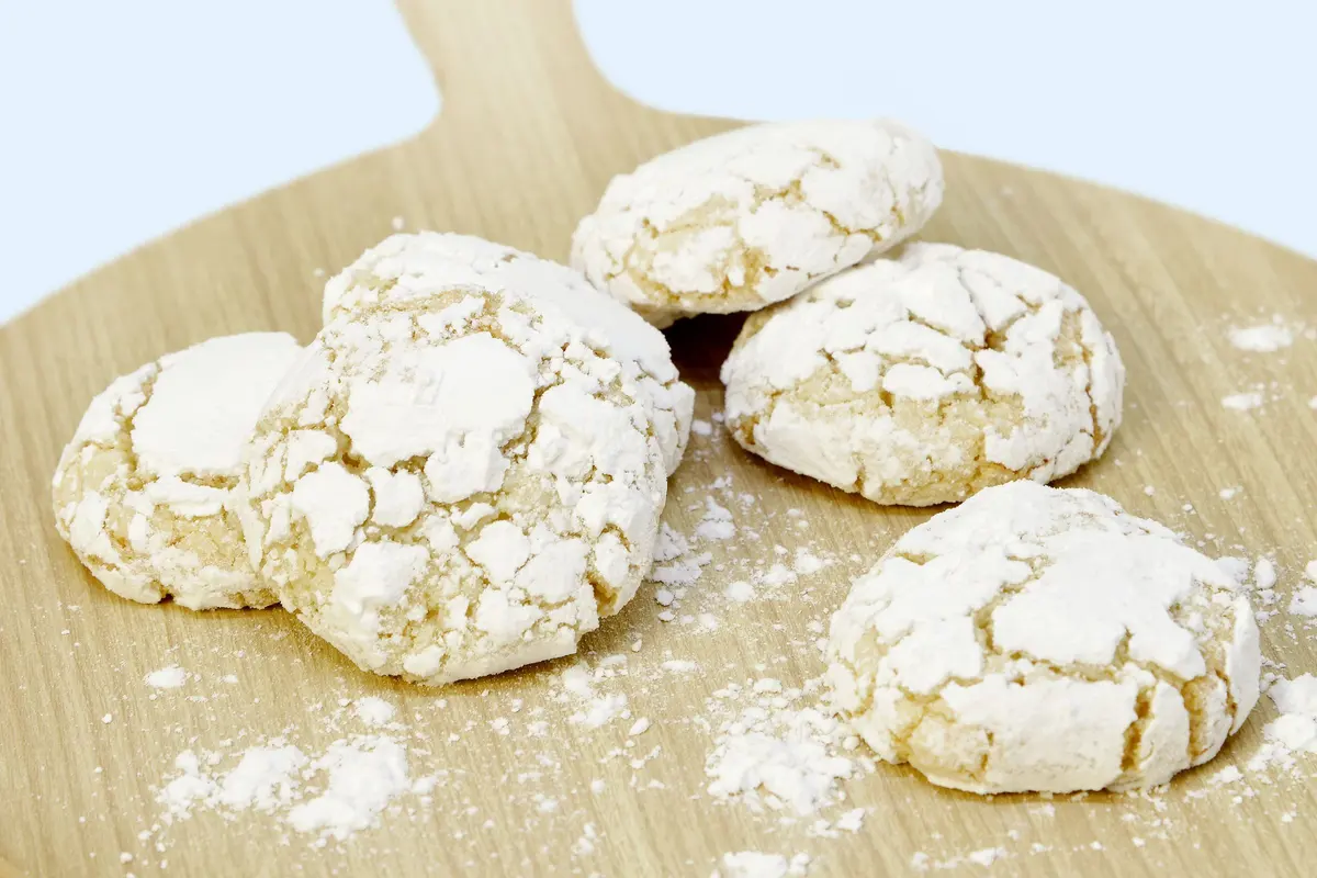 Amaretti morbidi screpolati coperti di zucchero a velo su un tagliere