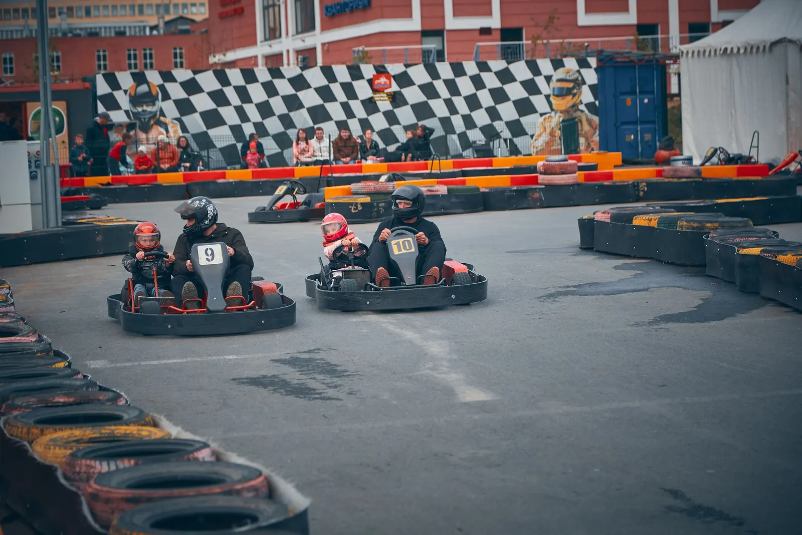 Adulti e bambini sui kart biposto in una pista all'aperto, con le gomme colorate a bordo