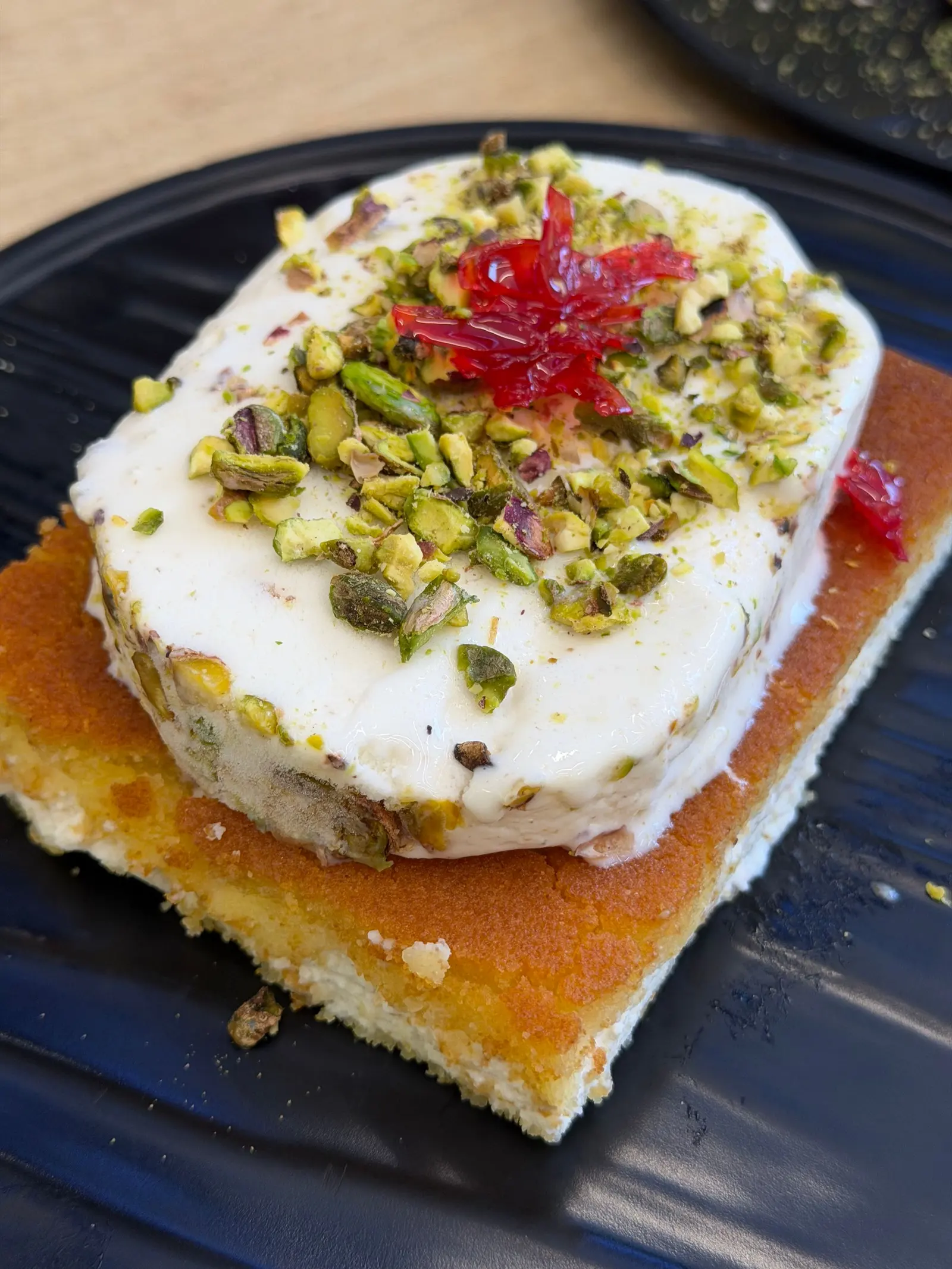 Una fetta di torta gelato al pistacchio su base di pan di Spagna, con granella sopra