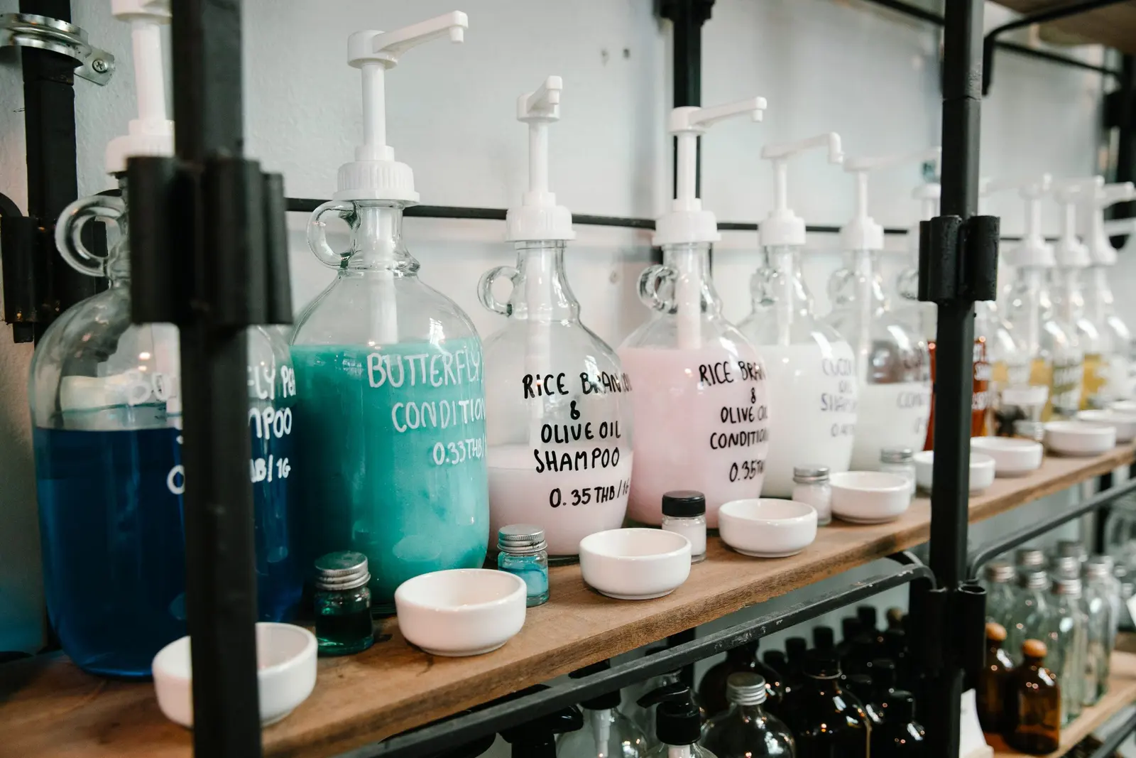 Una fila di grandi dispenser di shampoo colorati su una mensola di legno
