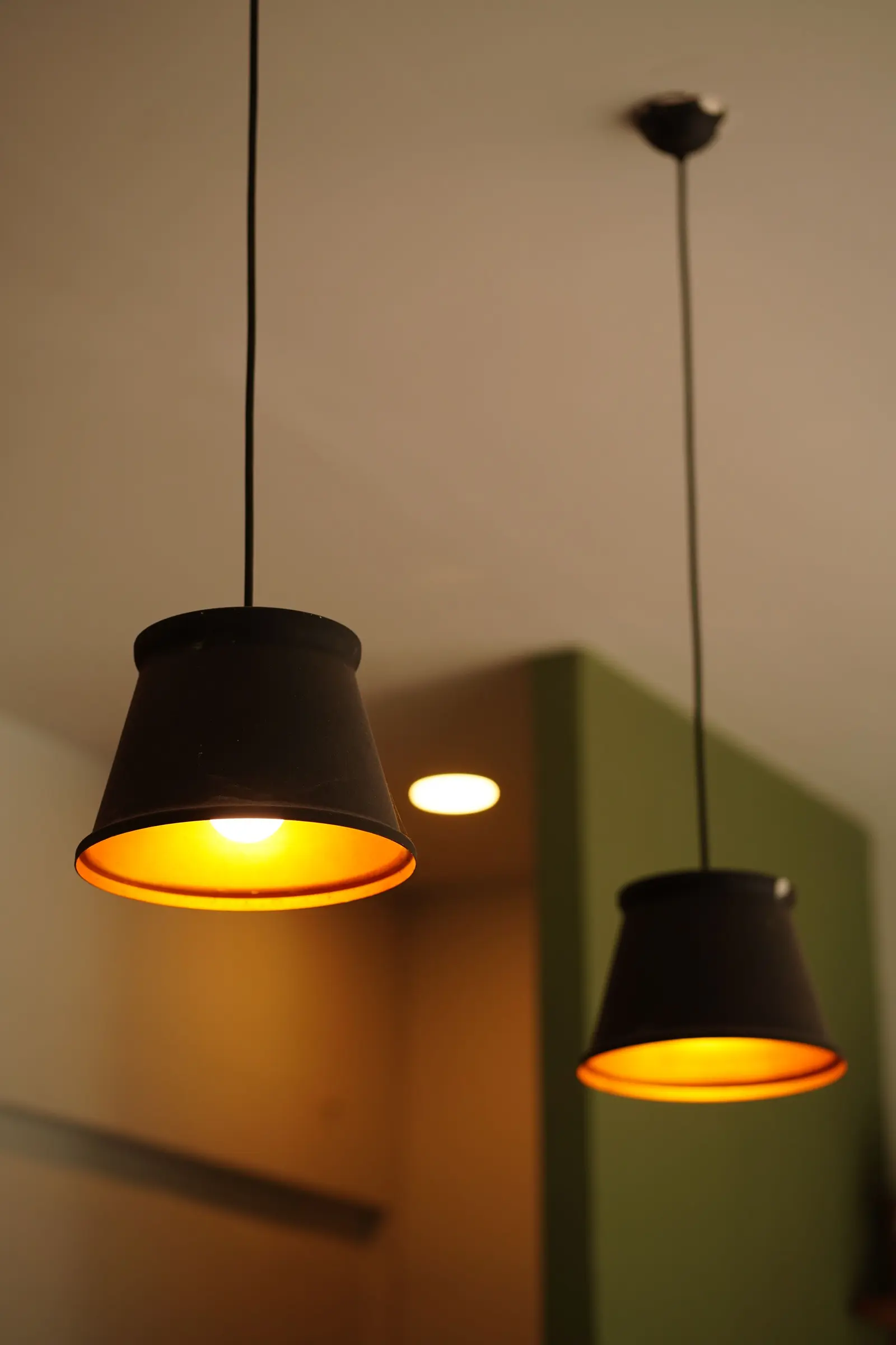 Due lampade a sospensione nere accese con luce calda in un soggiorno