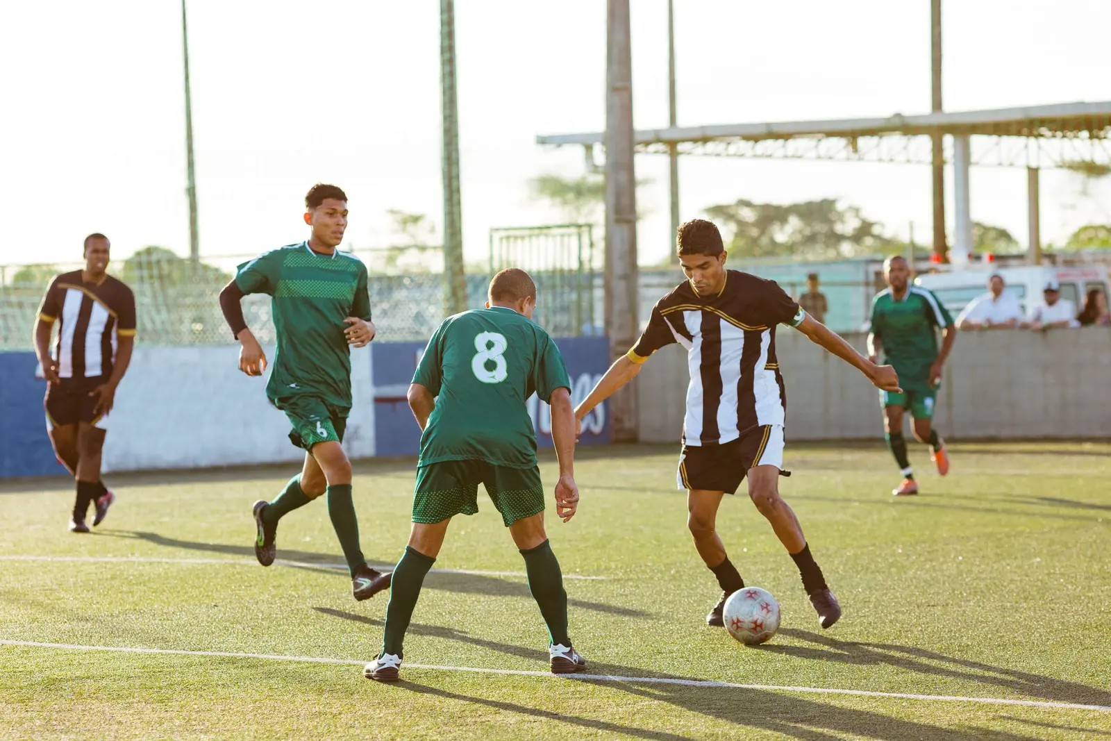 Partita di calcio a 5 di giorno: un giocatore in maglia a righe bianche e nere punta il difensore numero 8