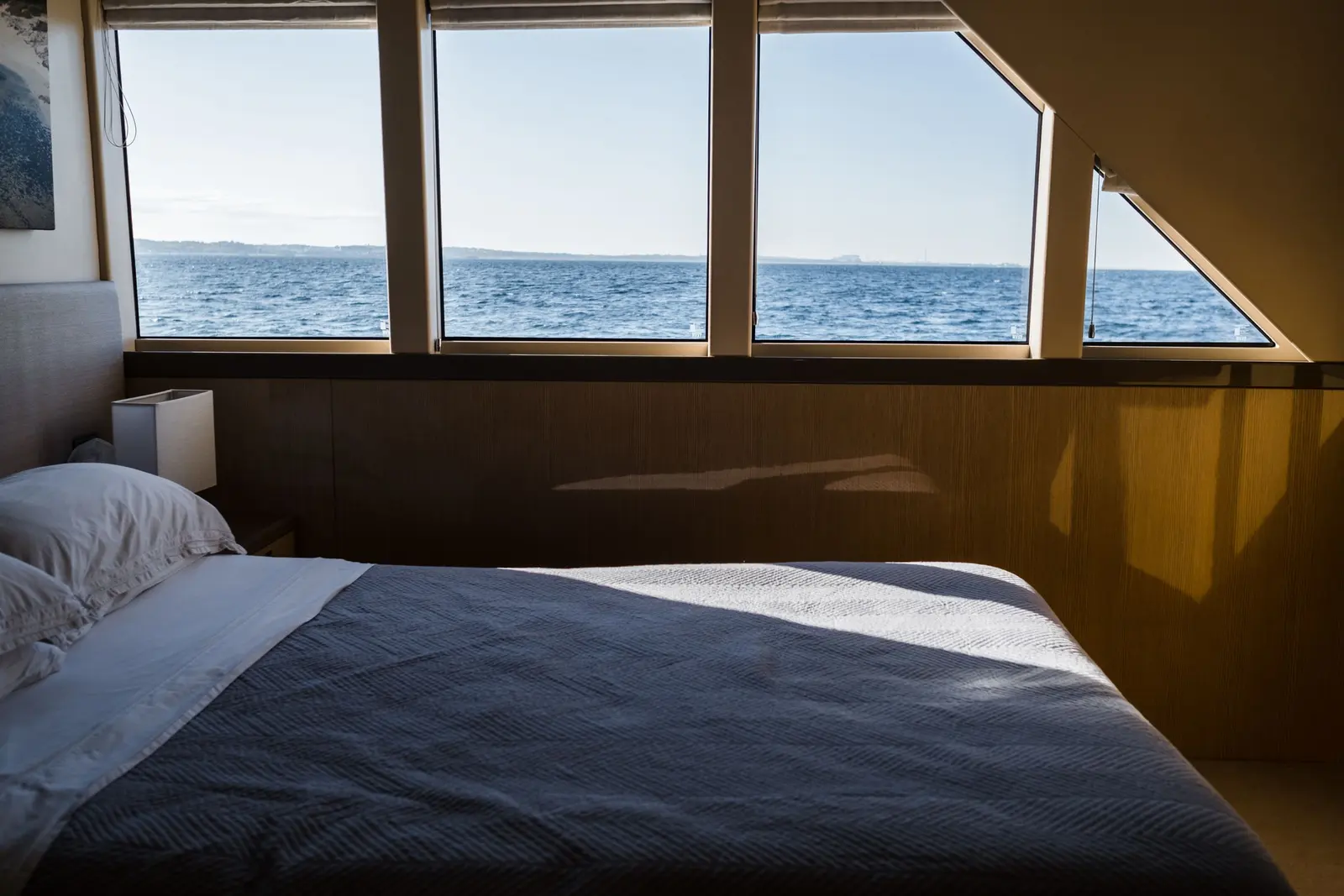Cabina armatoriale con finestrature sul mare e pannelli in legno chiaro