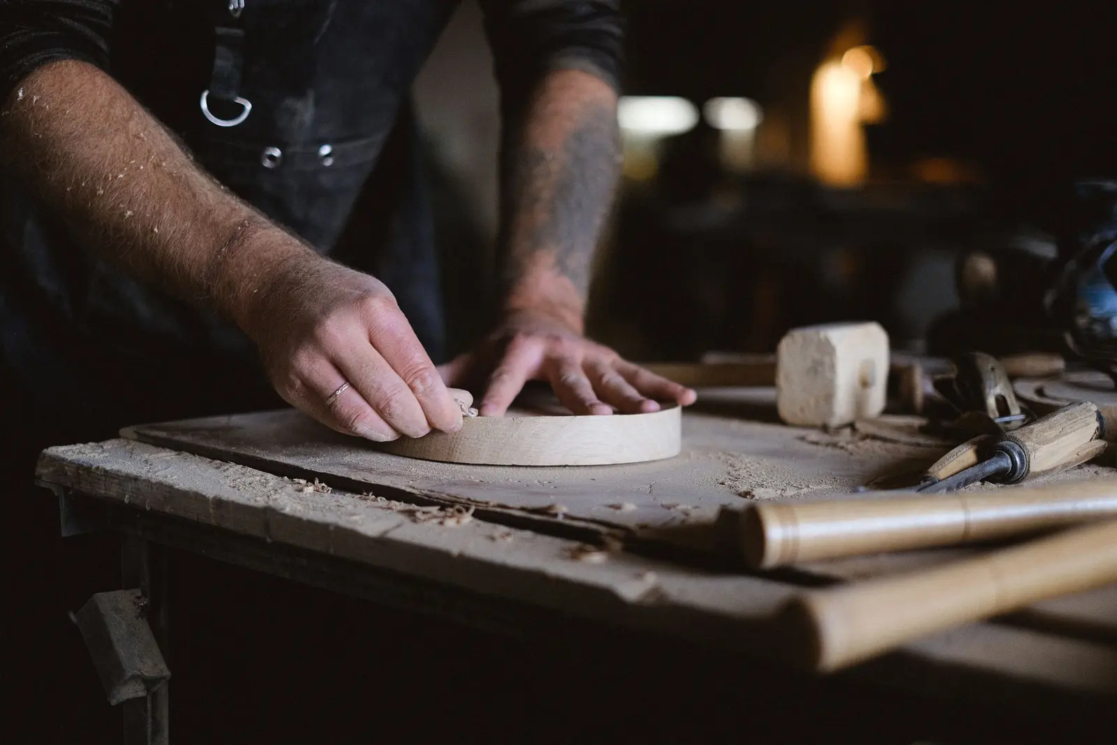 Mani che rifiniscono a mano un pezzo di legno sul banco