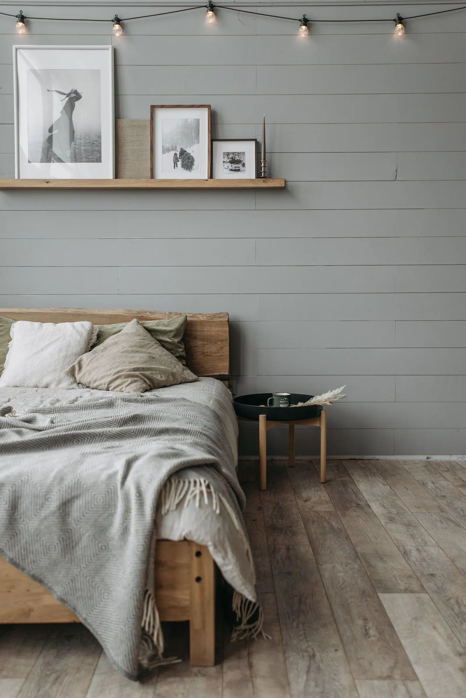 Letto con lenzuola di lino e coperta grigia contro una parete chiara