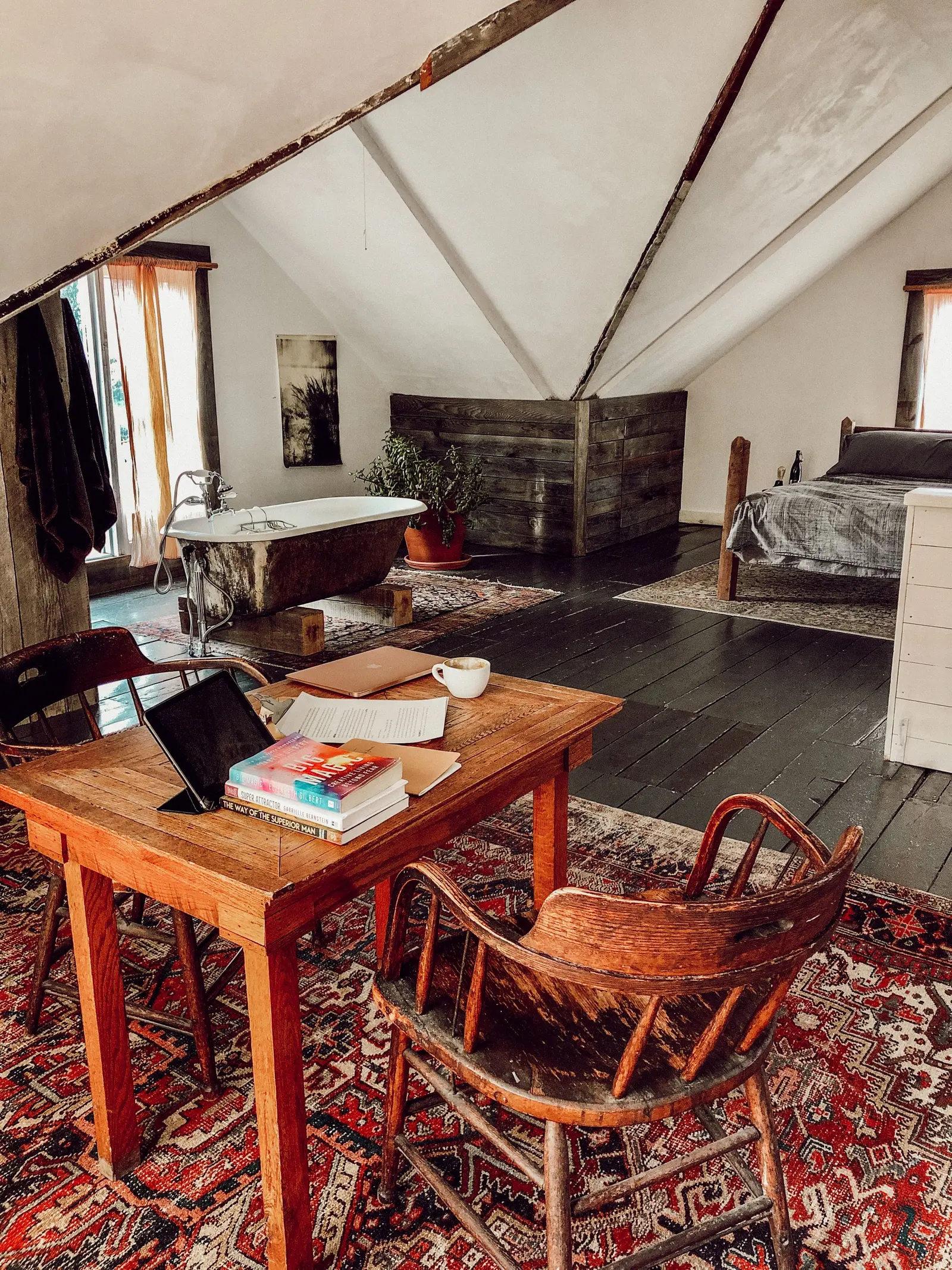 Stanza mansardata con tavolo di legno, tappeti e travi a vista