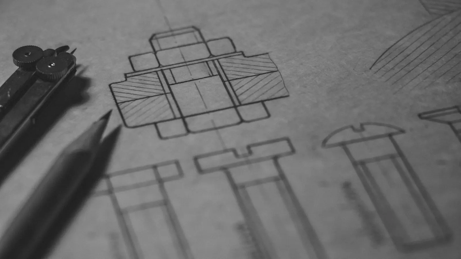 Disegno tecnico a matita con un compasso appoggiato sul foglio
